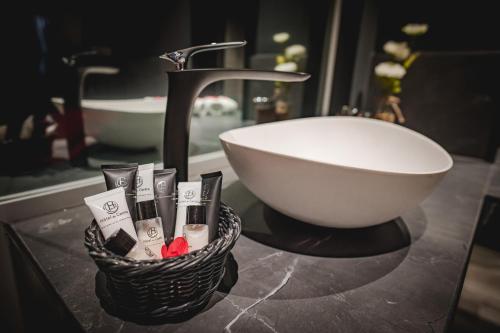 a bathroom counter with a sink and a basket of toiletries at Hôtel du Centre Appart hôtel Business avec Parking Gratuit à Nouméa in Noumea