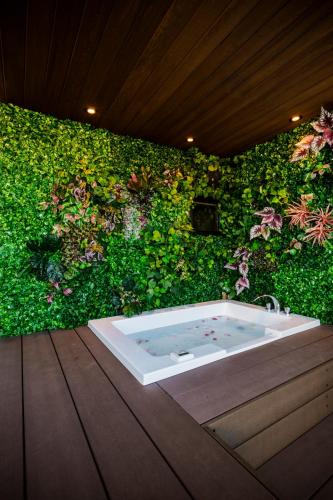 a bath tub in front of a green wall with flowers at ResoLife in Kochi