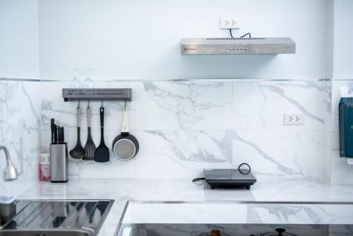 a kitchen with white marble walls and a sink at Turtle Tales-Tao Kra in Thai Muang