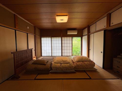 a bedroom with a bed in a room with a window at Yamaneko Lodge in Gujo