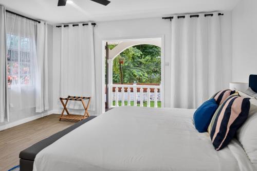 a white bedroom with a large bed and a window at Villa del Nique in Pembroke