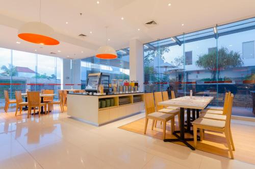 a restaurant with tables and chairs and windows at HARRIS Hotel and Conventions Denpasar Bali in Denpasar
