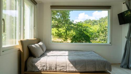 a bed in a room with a large window at Yangyang Slowstay Pension in Yangyang