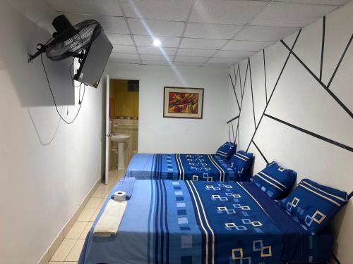 a bedroom with two beds with blue sheets and a spotlight at Hospedaje Lima Suite in Piura