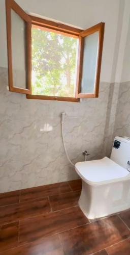 a bathroom with a white toilet and a window at Nivriti Stays in Nainital