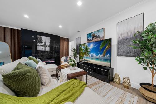 a living room with a white couch and a flat screen tv at Entire Private House with King Bed, 80 TV, Gated Yard, Ranch Style, 4 Bedrooms 2 Bathrooms, Available Now in El Cajon