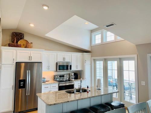 a kitchen with white cabinets and a stainless steel refrigerator at The Seventh Day in Holden Beach