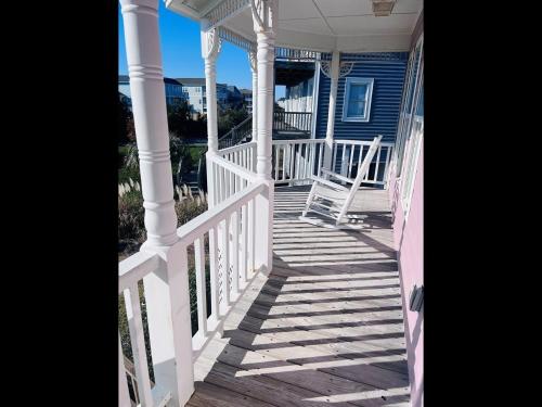 a porch with white railings on a blue house at Victoria in Holden Beach