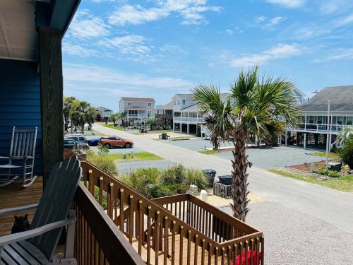 a balcony of a house with palm trees and a street at Tradewinds in Holden Beach