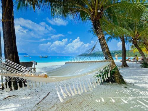 a hammock on a beach with palm trees at Home Escape Resort in Phumĭ Bát Tráng (2)