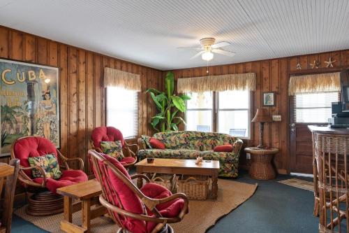 a living room with red chairs and a couch at Yellow Bird in Holden Beach