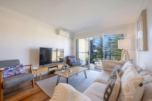 a living room with a couch and a tv at Seaspray Views - Lifestyle Yamba in Yamba