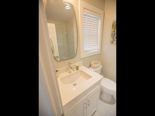 a bathroom with a sink and a toilet and a mirror at Three Girls in Holden Beach