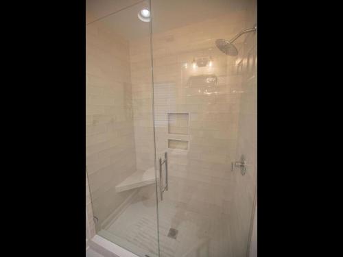 a shower with a glass door in a bathroom at Three Girls in Holden Beach
