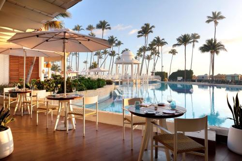 a restaurant with tables and chairs next to a swimming pool at Paradisus by Meliá Palma Real Golf and Spa Resort - All Inclusive in Punta Cana