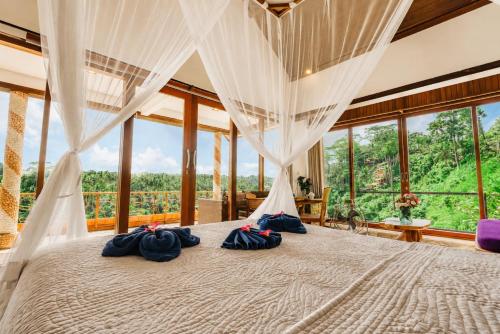 a bedroom with a large bed with a large window at River Song Ubud, Bali in Ubud