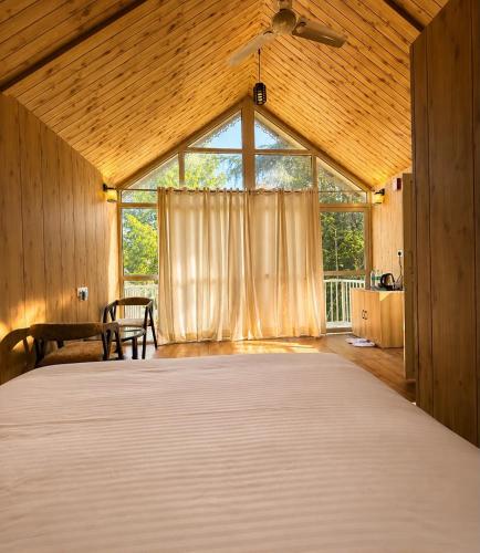 a large bed in a room with a large window at Treehouse by the lake in Bhīm Tāl
