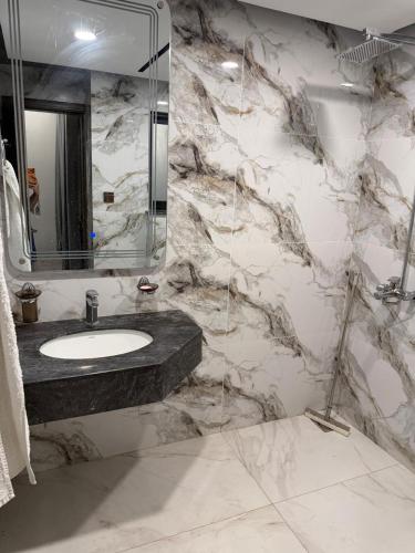 a marble bathroom with a sink and a mirror at Emanzara in Islamabad