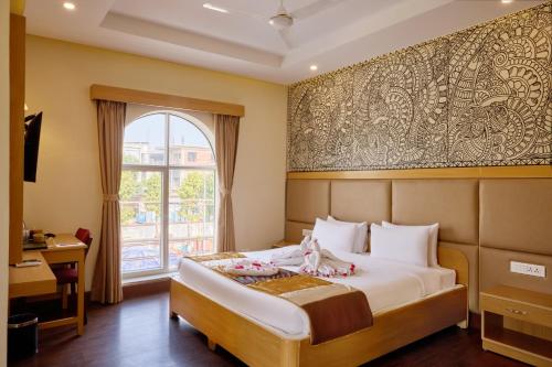 a hotel room with a bed and a window at Mithila Yatri Niwas in Janakpur