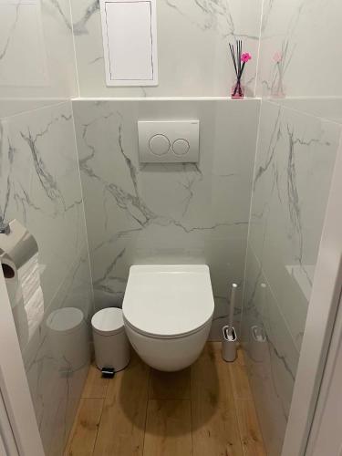 a bathroom with a white toilet and marble walls at Apartament Rubinkowo in Toruń