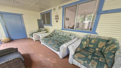 a patio with a couch and chairs on a porch at Beachside Bungalow in Minnie Water