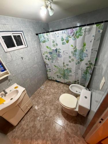 a bathroom with a toilet and a sink and a shower curtain at La Cumbre in Chos Malal