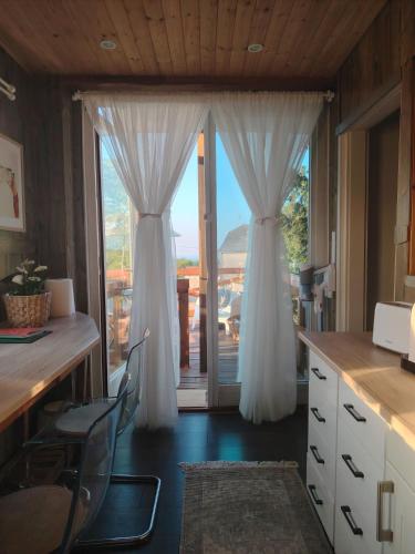a kitchen with white curtains and a large window at Lombfészek in Rezi