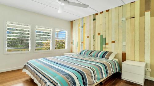 a bedroom with a bed and two windows at Moomba On Main in Wooli
