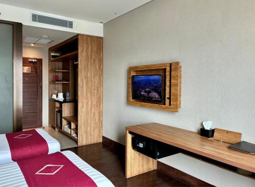 a hotel room with a bed and a desk at Emersia Hotel & Resort Batusangkar in Batusangkar