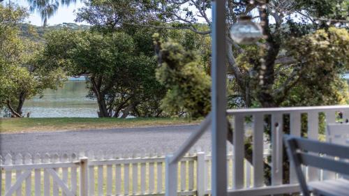 a white fence next to a road with a bench at Wooli House in Wooli