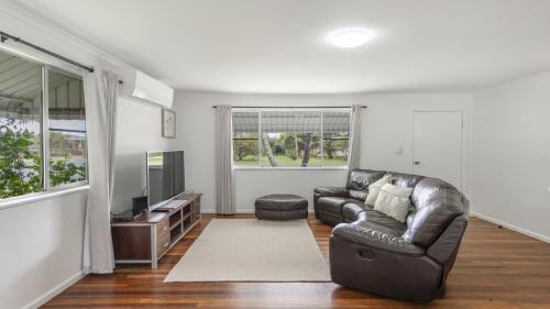 a living room with a leather couch and a television at Twin Palms Retreat in Wooli