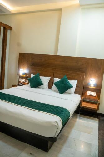 a bedroom with a large bed with green pillows at Hotel CP Residency in Agra