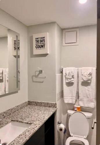 a bathroom with a sink and a toilet and a sign at The Grand suite in Portmore