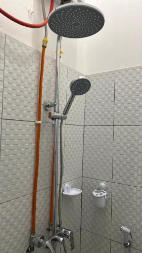 a shower with a shower head in a bathroom at Naeera Inn Wonosobo Dieng in Kalibeber