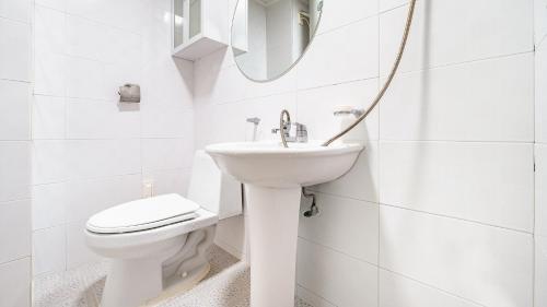a white bathroom with a toilet and a sink at Geoje Youngsu Pension in Geoje