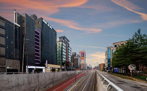 an empty city street with tall buildings and a cloudy at Brown Dot Hotel Guun in Suwon