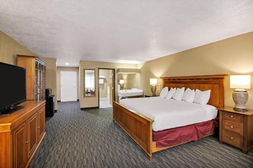 a hotel room with a bed and a television at Days Inn & Suites by Wyndham Logan in Logan