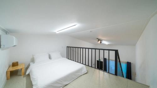 a white bedroom with a bed and a balcony at GaPyeong Yeoldudal Spapension&Camping in Gapyeong
