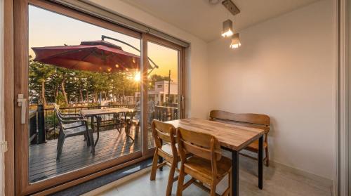 a dining room with a table and chairs on a balcony at Samcheok The Ggeullim Pension in Samcheok