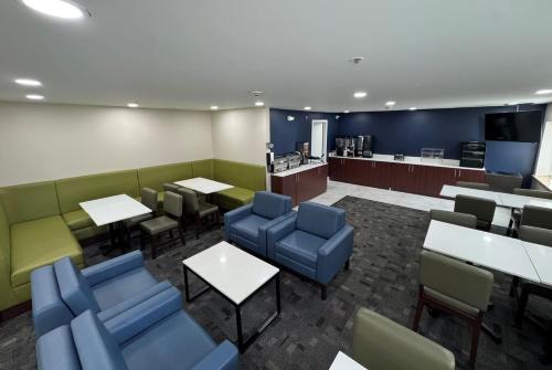 a waiting room with blue chairs and tables and a cafeteria at La Quinta Inn by Wyndham Auburn Worcester in Auburn