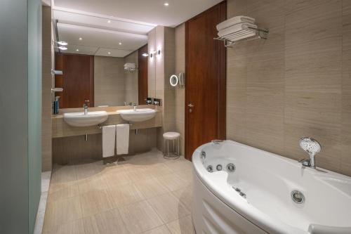 a bathroom with two sinks and a tub and a mirror at DoubleTree by Hilton Turin Lingotto in Turin