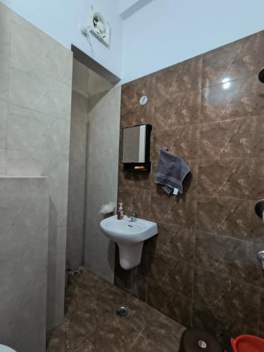 a bathroom with a sink and a tv on the wall at The Global Nest Homestay 