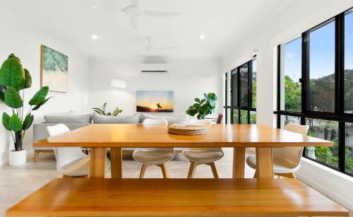 a dining room with a wooden table and windows at Palm Cove Retreat I heated pool I Family home in Palm Cove