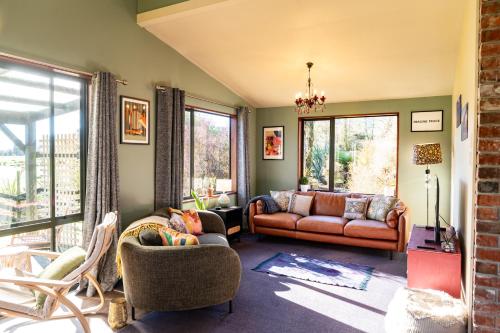 a living room with a couch and chairs and windows at Waimanu Guest House in Franz Josef