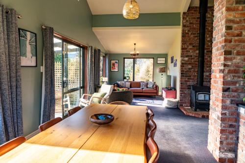 a living room with a wooden table and a fireplace at Waimanu Guest House in Franz Josef