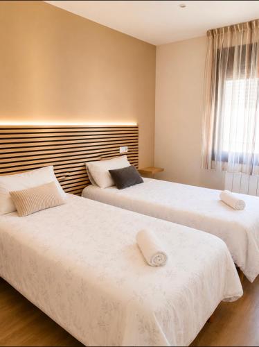 a bedroom with two beds with white sheets and a window at Conde de Lerín by Clabao in Lerín
