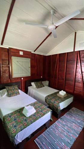a room with three beds and a ceiling fan at Conjá Ecolodge in Porto Alegre