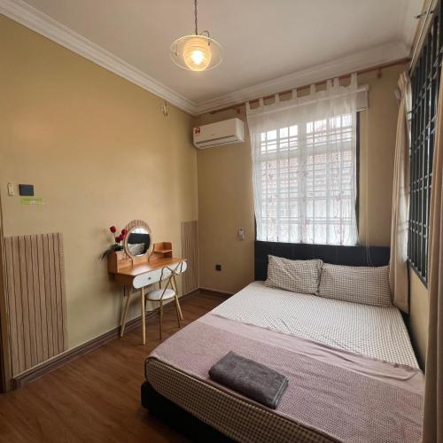 a bedroom with a bed and a desk and a window at Homestay by Tas in Kulai