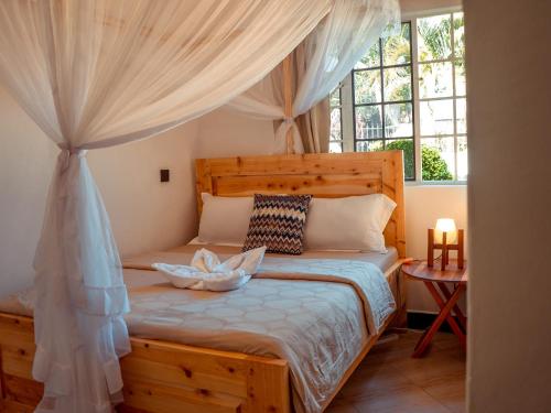 a bedroom with a wooden bed with a canopy at Nam's Homestay in Arusha