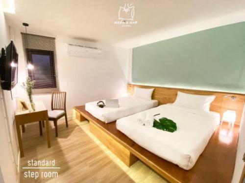 a hotel room with two beds and a desk at Need a Nap Hostel Phrae in Phrae